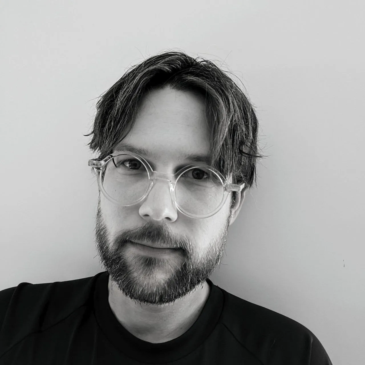 A black and white portrait of Jonathon Toon, wearing glasses.